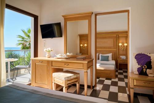 a bedroom with a desk and a bed with a mirror at EVLOGIA HOTEL SEAFRONT and ANEX by Greek Pride in Fourka