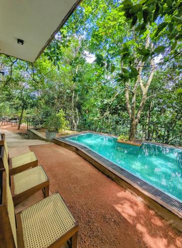 a swimming pool in a yard with two chairs at Trance rabara resort in Avissawella