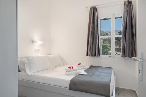 a white bedroom with a bed and a window at Country House Apartments in Ios Chora
