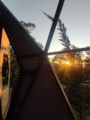 a view of the sunset through the window of a house at Chalé Refugio da Pedra SP in São Bento do Sapucaí