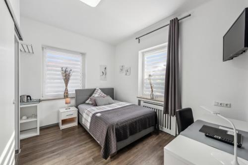a bedroom with a bed and a desk and a tv at Diepholzer Boardinghouse by BohnApartments - Parkplätze - WLAN - Garten - ruhig in Diepholz