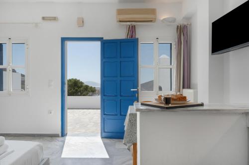 a blue door in a white room with a kitchen at Country House Apartments in Ios Chora