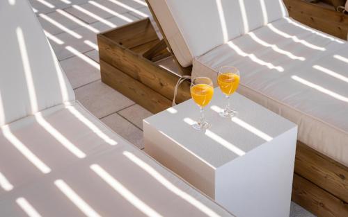 two glasses of wine on a table next to a bed at Morfes Luxury Apartments in Triandáros