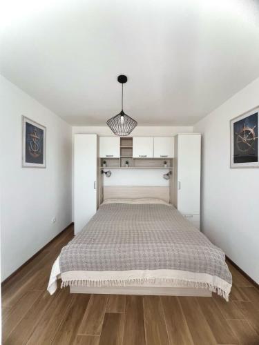 a white bedroom with a bed and a chandelier at Vranac Country house Šibenik in Donje Polje