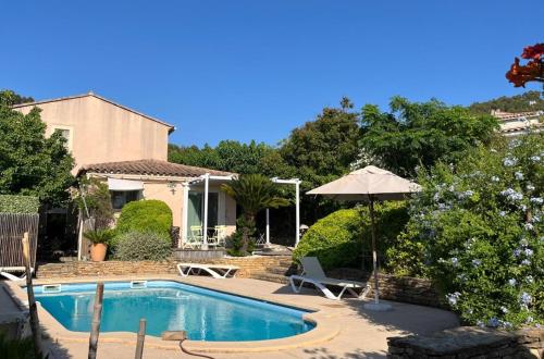 - une piscine avec un parasol et une maison dans l'établissement Les Oliviers - Ceyreste, à Ceyreste