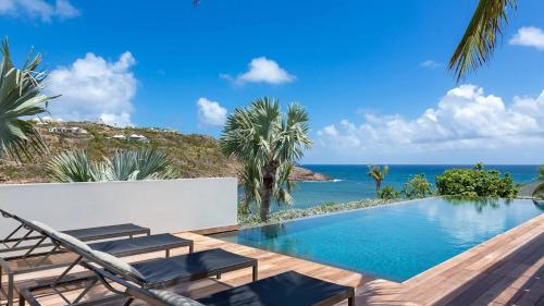 a pool with chairs and the ocean in the background at Marigot Bay Oasis with Infinity Pool in Marigot