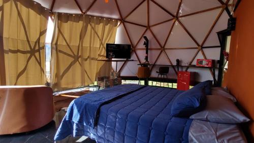 a bedroom with a blue bed in a yurt at Chalé Refugio da Pedra SP in São Bento do Sapucaí