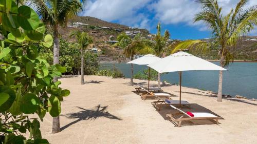 a row of chairs and umbrellas on a beach at Marigot Bay Oasis with Infinity Pool in Marigot