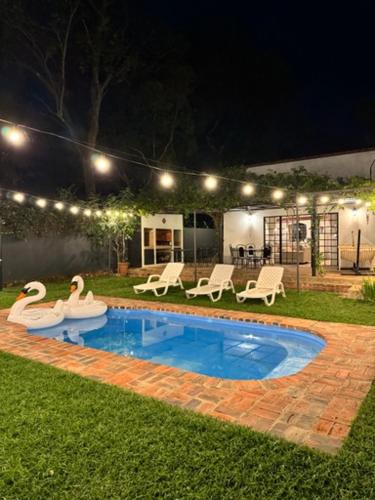 a pool with two swans in a yard at night at Encantadora Casa De Verano - Marilaf in San Bernardino