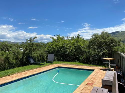 a swimming pool with a table and chairs next to it at Sani Lodge & Cottages in Sani Pass