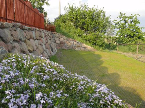 a garden with purple flowers and a stone wall at Domek Piaski Nad Morzem in Krynica Morska