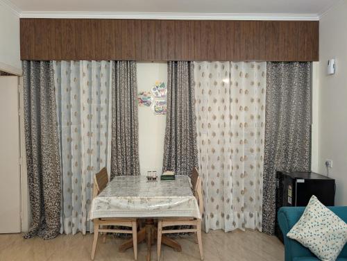a dining table in a living room with curtains at Golden Hour Hideaway in Greater Noida