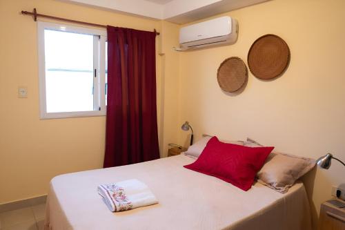 a bedroom with a bed with red pillows and a window at Departamento a 5 min del Centro in Posadas