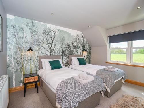 two beds in a room with a large window at Hill View at Kenmuir in Dalbeattie