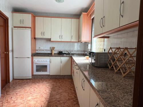 a kitchen with white cabinets and a white refrigerator at Coastine Granada - Casa con vistas al mar en Castell de Ferro in Castell de Ferro