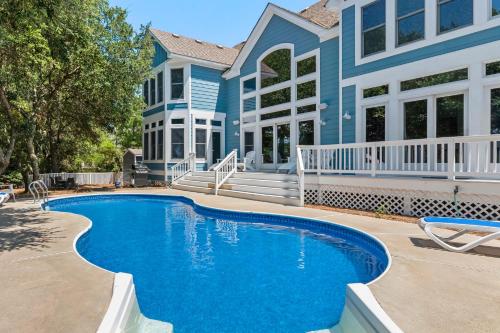 a house with a swimming pool in front of a house at Beach ParTee Time in Corolla