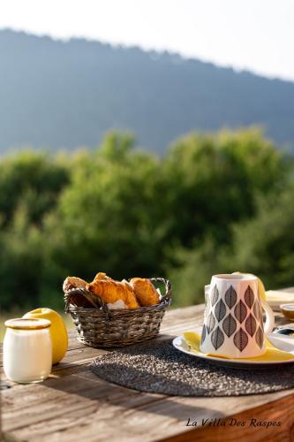 a table with a basket of pastries and a cup of coffee at La Villa Des Raspes - Séjour Spa - Adult Only in Viala-du-Tarn