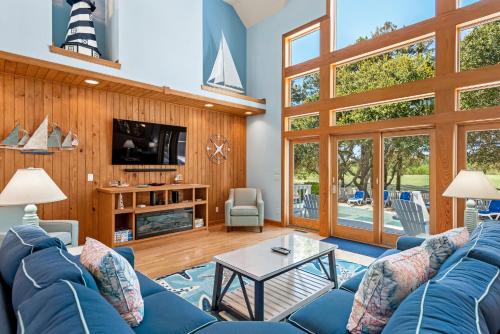 a living room with a blue couch and a tv at Beach ParTee Time in Corolla