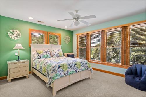 a bedroom with green walls and a bed and a fan at Beach ParTee Time in Corolla