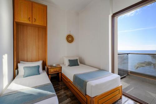 a bedroom with two beds and a balcony with the ocean at EVLOGIA HOTEL SEAFRONT and ANEX by Greek Pride in Fourka