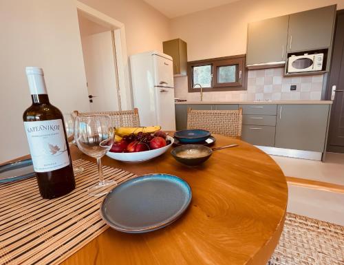 a table with a bottle of wine and a bowl of fruit at Spitaki Among Olives in Tsoukalades