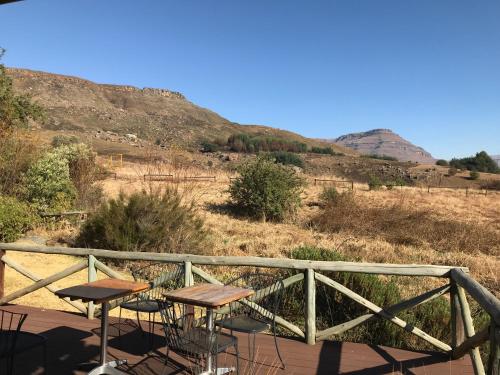 a balcony with two tables and a view of a hill at Sani Lodge & Cottages in Sani Pass