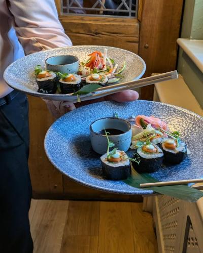 a person holding two plates with food on them at The Plough Inn & Restaurant in Congleton