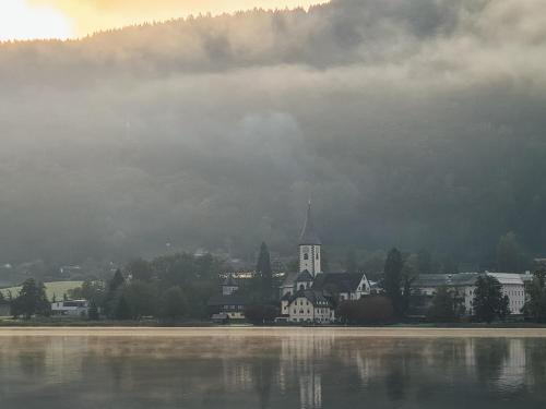 a town next to a body of water with a church at Haus Kleinod in Bodensdorf