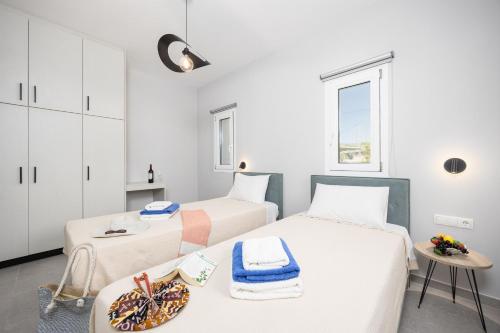 2 letti in una camera con pareti bianche e un tavolo di Villa Tania Dio a Karavádhos