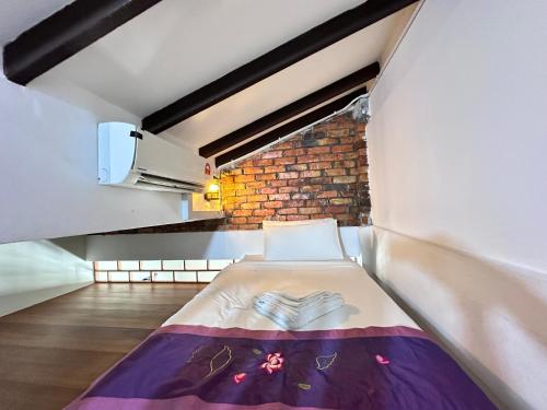 a bed in a room with a brick wall at 26 Rangoon Residence 26 in George Town