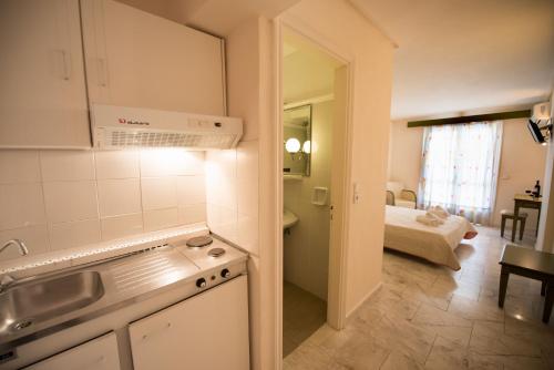 uma cozinha com um lavatório e um quarto com uma cama em Hotel Niras em Nydri