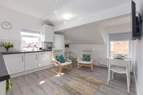 a kitchen with white cabinets and a table and chairs at Lytham St Annes Luxury Apartment - No 3 Tides Reach in Lytham St Annes