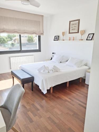 a white bedroom with two beds and a chair at Villa Serenità by Prolocal in Cunit