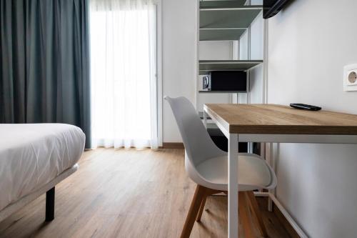 a bedroom with a bed and a desk and a bed and a table at Hotel Calella by Beatriz Hoteles in Calella