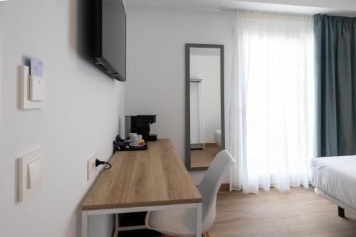a room with a table and a mirror and a bed at Hotel Calella by Beatriz Hoteles in Calella