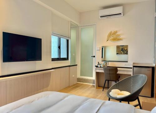 a bedroom with a bed and a desk and a television at Choozme in Lugang