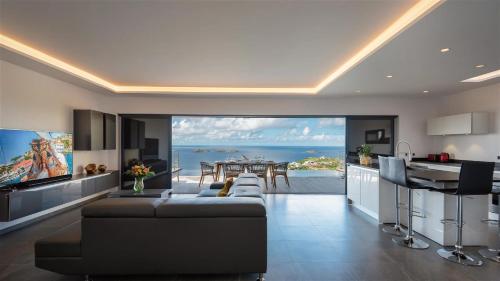 a living room with a large couch and a kitchen at Unparalleled Luxury Villa with Ocean Vistas in Vitet in Quartier de Lorient