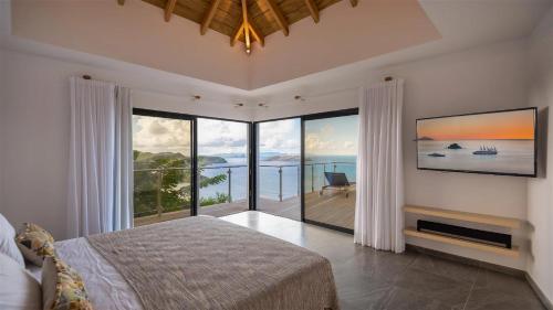 a bedroom with a bed and large glass windows at Unparalleled Luxury Villa with Ocean Vistas in Vitet in Quartier de Lorient
