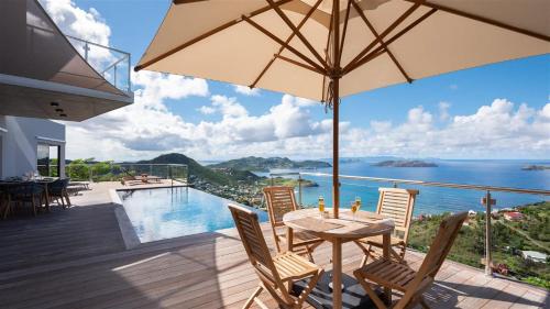 a patio with a table and chairs and a view of the ocean at Unparalleled Luxury Villa with Ocean Vistas in Vitet in Quartier de Lorient