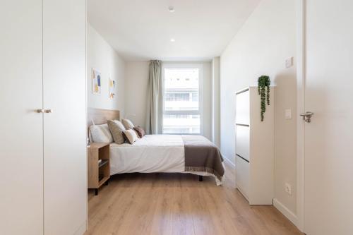 a white bedroom with a bed and a window at Bext Valdebebas in Madrid