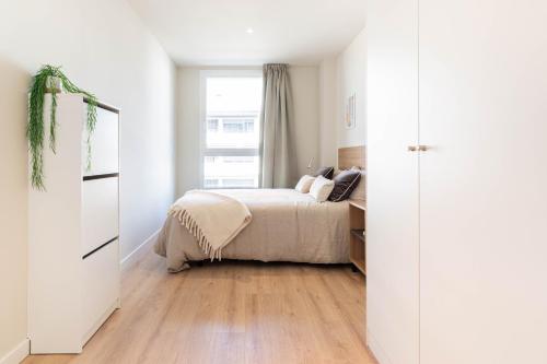 a white bedroom with a bed and a window at Bext Valdebebas in Madrid
