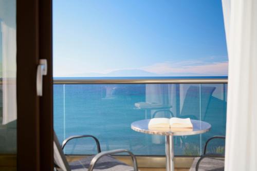 a balcony with a table and chairs and a view of the ocean at EVLOGIA HOTEL SEAFRONT and ANEX by Greek Pride in Fourka