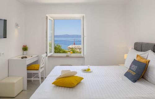 a white bedroom with a large white bed and a window at Apartments Amfora 2 in Podgora