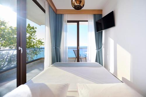 a bedroom with a bed with a view of the ocean at EVLOGIA HOTEL SEAFRONT and ANEX by Greek Pride in Fourka