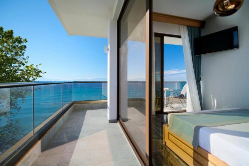 a bedroom with a balcony with a view of the ocean at EVLOGIA HOTEL SEAFRONT and ANEX by Greek Pride in Fourka