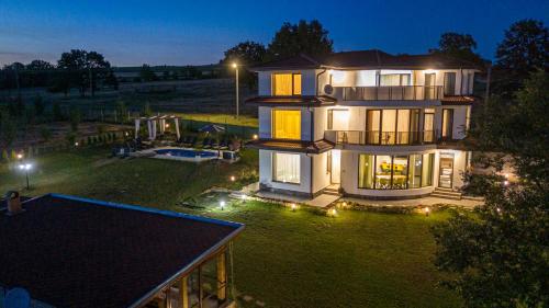 a large house with lights on a yard at night at Къща за гости Гардения in Kamburovo