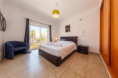 a bedroom with a bed and a chair and a window at C02 - Luxury 3 Bed with Pool View in Lagos
