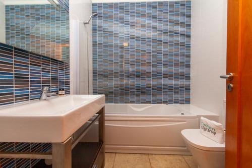 a bathroom with a sink and a tub and a toilet at C02 - Luxury 3 Bed with Pool View in Lagos