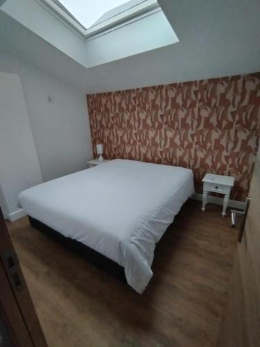 a bedroom with a large white bed and a skylight at Le Familia in Guer
