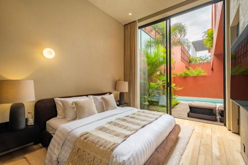 ein Schlafzimmer mit einem Bett und einem großen Fenster in der Unterkunft Five Stories Villas By SUOM in Canggu